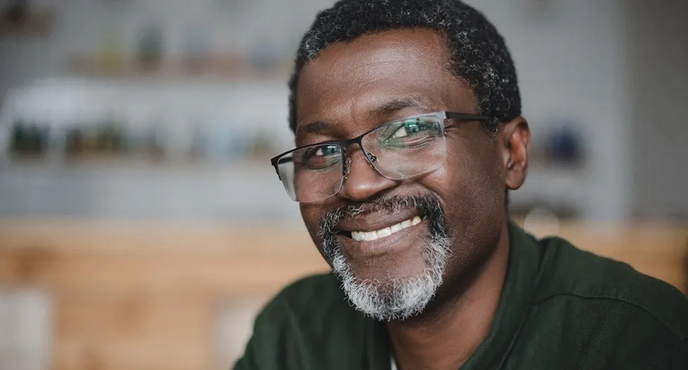 A middle-aged man wearing glasses and smiling in preparation for seeing his Cigna dentist in Park City