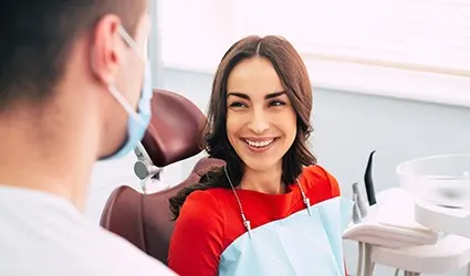 A female patient smiles at her dentist while he goes over her treatment plan