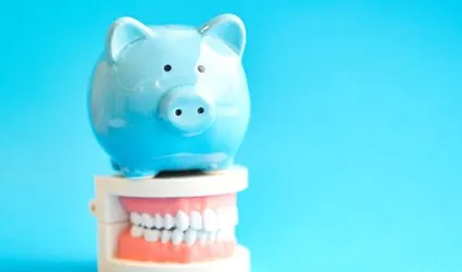 blue piggy bank sitting on a set of false teeth