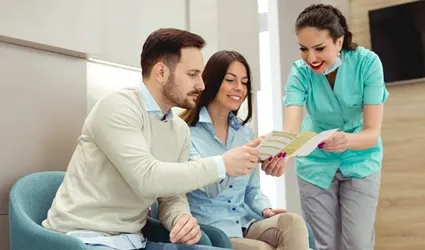 dental team member showing a pamphlet to two patients