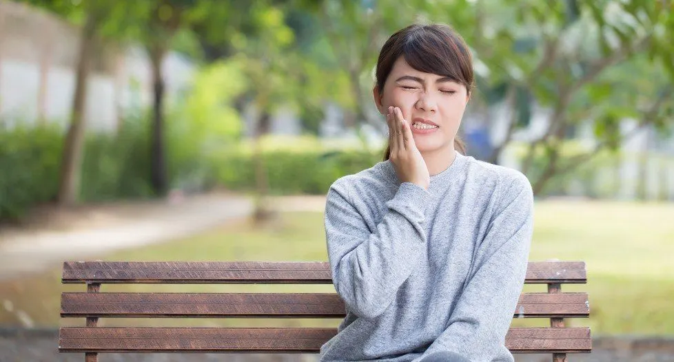 Woman holding cheek in pain