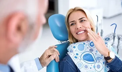 Woman in dental chair holding cheek