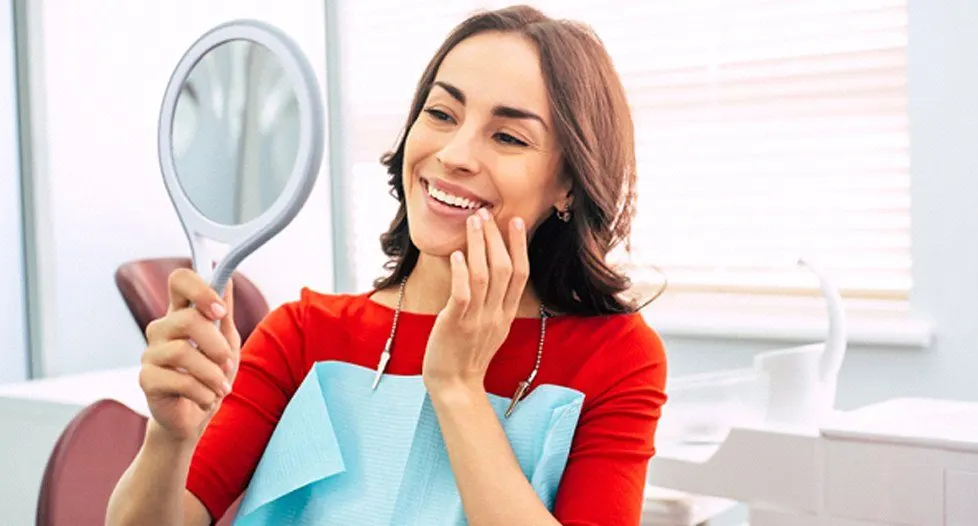 Woman checking smile after dental implant salvage