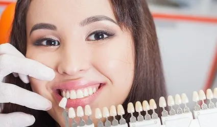 Woman's smile compared with tooth color chart
