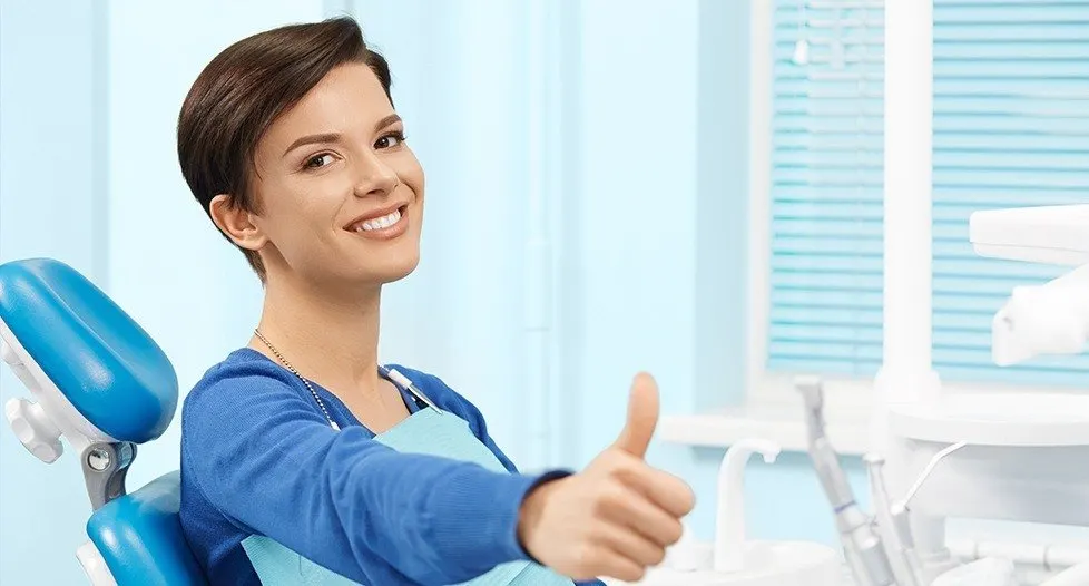 Woman in dental chair giving thumbs up