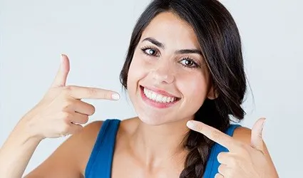 Woman pointing to her smile