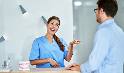 A dental receptionist discussing scheduling and dental insurance with a male patient