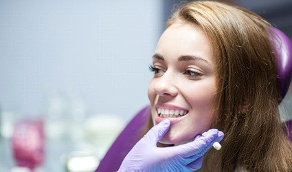 A dentist looking at a young woman’s smile